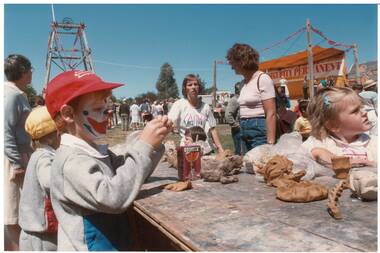 Close-up, children modelling clay, two adults supervising, outdoors, poppet head in background.