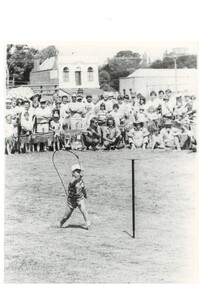Black and White image of Daniel Young aged 4 of Toongabbie in Whip Cracking competition showing spectators and the 2nd storey of Old Eagle Hotel in background without balcony