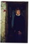 Middle-aged lady in dark jumper standing in gloomy doorway of painted brick cellar.