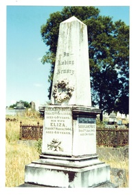 Stone monumnet square pillar on plinth, pyramid top, ornate carved wreath decoration.