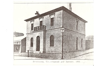 Two story rendered bank building, slightly extended entrance portico  topped with iron balcony, ground floor flanked by arched windows, upper floor rectangular windows, gas lamp on corner of footpath.