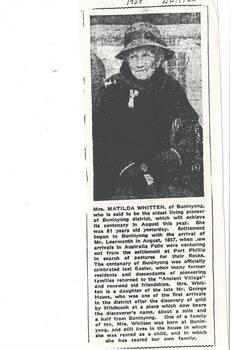 Newspaper article with monochrome photo of elderly lady wearing felt brimmed hat with dark band, black coat with fur collar, gloves and handbag.