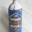 Blue coloured cylinder with rounded base and painted white neck. A large blue on white diamond shaped label is adhered onto the body.