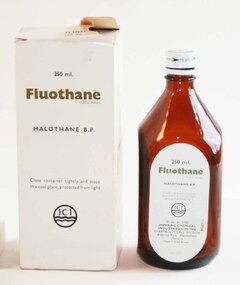 An empty brown glass bottle stands next to a white carboard box. Both have distinct green labelling.