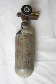 Empty small pale green painted cylinder with rounded base and attached outflow valve with circular 'On-Off' knob.
