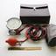 Long strands of black and red rubber tubing, are attached to a gauge at one end, and a fabric cuff at the other, with a leather carry bag sitting behind them.