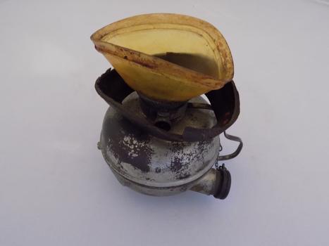 The leather padding around the yellow mouthpiece of this Hewitt Inhaler has degraded and fallen onto the round container to which it is attached.