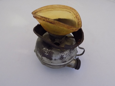 The leather padding around the yellow mouthpiece of this Hewitt Inhaler has degraded and fallen onto the round container to which it is attached.