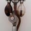 Two glass bulbs are attached to a metal connector, with a red rubber tube running through the centre point, over a gauge/