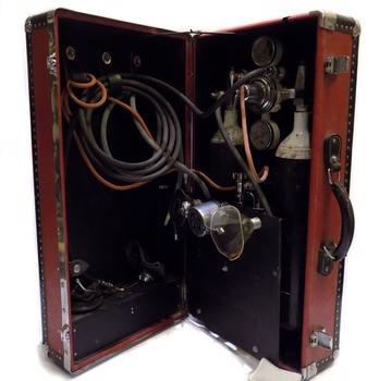 The inside of the red leather suitcase with black leather trim with metal studs, reveals a collection of facemasks tubing and space for oxygen cylinders.