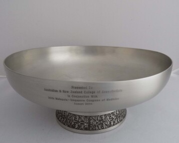 Pewter bowl on raised round base with silver plated decorated inlay in an ornate flowery scroll pattern.