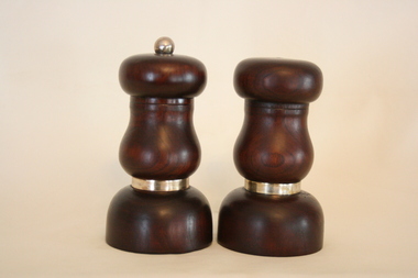 A pair of hand crafted red cedar salt and pepper shakers, each with a thin gold band above the base.