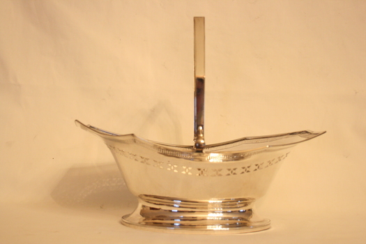 Silver plated copper basket with swing handle, with a geometric and circular pattern around the brim and a phoenix engraved into the handle.