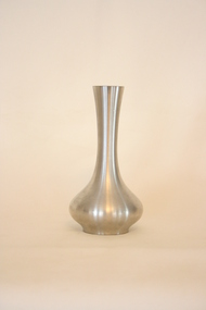 A small, fluted vase made from pewter, with a soft sheen.