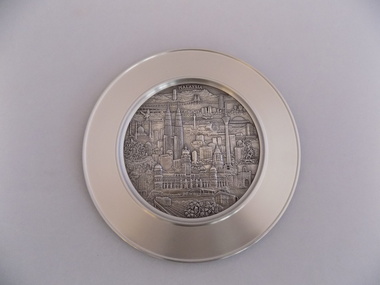 Pewter plate with embossed central image of modern day Malaysia city landscape.