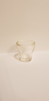 Small clear glass container with a round base, extending into an oval shaped opening