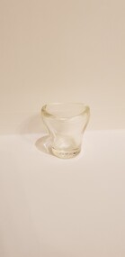Small clear glass container with a round base, extending into an oval shaped opening