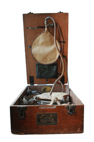 The reddish wood box is scratched and dented, and contains a system of rubber tubing and metal elements which act as an artificial respiration machine.