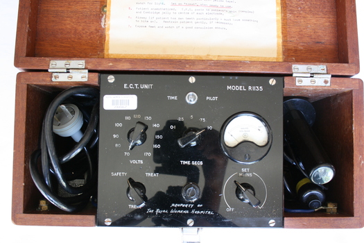 Inside the box, the machine itself is revealed to be a square black metal plate, affixed to the side walls of the box and with space underneath to store the electrical cables and handles.
