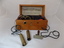Wooden box containing a magnet with wires connected to metal handles, intended to provide a mild shock to the holder.