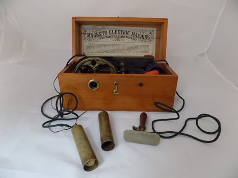 Wooden box containing a magnet with wires connected to metal handles, intended to provide a mild shock to the holder.