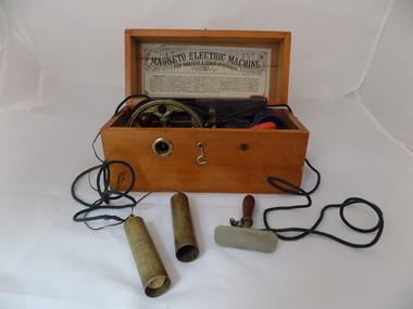Wooden box containing a magnet with wires connected to metal handles, intended to provide a mild shock to the holder.