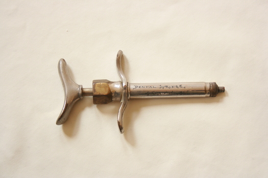 A metal dental syringe.