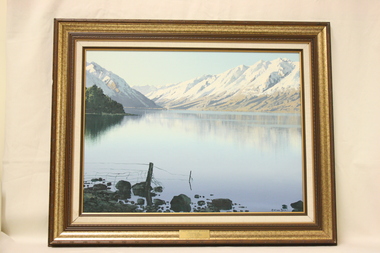 An oil painting depicting Lake Ohau and mountain scenery in a gold and bronze frame.