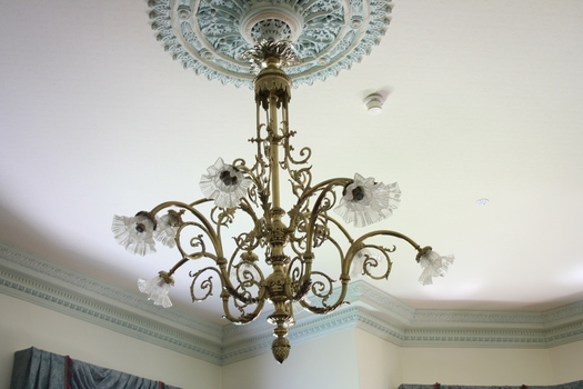 An ornate chandelier hanging from a mount on the ceiling.