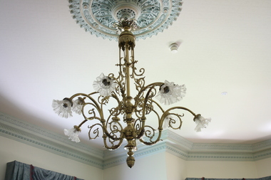 An ornate chandelier hanging from a mount on the ceiling.