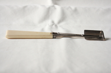 A sterling silver and ivory cheese scoop.