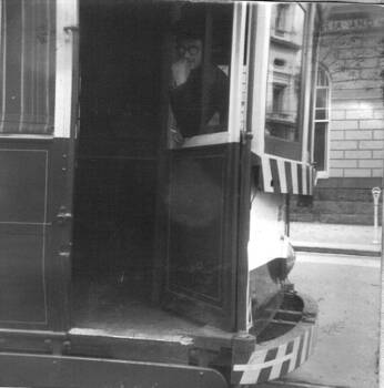  motorman leaning out the small window with a cigarette in hand.  