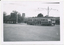  vintage tram with the number 117 is stopped on a street in front of a brick building and trees. The tram has large windows and multiple doors along its side.