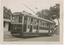 Shows tram numbered 29. The tram has several windows and appears to be stopped at a depot, with a building to the left and trees in the background.