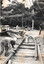 Men in hard hats work on laying tram tracks, with a crane in the background. They are using tools to position the metal rails onto wooden sleepers.