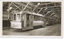 A number of vintage trams are parked indoors, with one bearing the text "VICTORIA ST", "GOLD CENTENARY" and "100 YEARS" and "1851 - 1951". The trams are in a large shed with wooden beams supporting the roof.