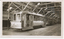 A number of vintage trams are parked indoors, with one bearing the text "VICTORIA ST", "GOLD CENTENARY" and "100 YEARS" and "1851 - 1951". The trams are in a large shed with wooden beams supporting the roof.