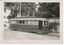 tramcar numbered 30 with multiple windows and an open door, parked on tracks outdoors with trees and a building in the background.