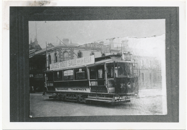 A vintage Ballarat Tramways tram is parked on a street in front of a building. A banner advertising a "JACOS BOOT SALE" is stretched across the side of the tram.