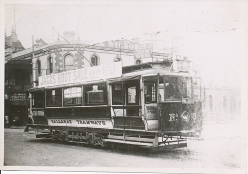 A vintage Ballarat Tramways tram is parked on a street in front of a building. A banner advertising a "JACOS BOOT SALE" is stretched across the side of the tram.
