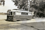 A vintage electric tram, number 17, with "Victoria St" displayed on its front, is parked on a track next to a body of water and trees. A vintage car is visible parked behind the tram.