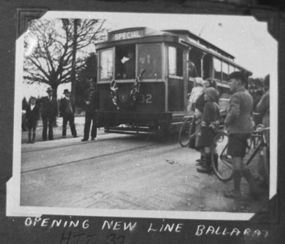 A vintage tramcar labeled "SPECIAL" with the number 32 on its side, stopped on tracks beside a group of men and children, with a few bicycles nearby.