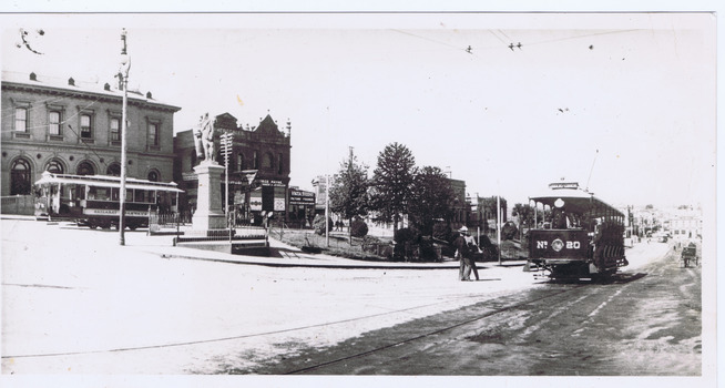 A street scene with a tram labeled "Nº 20" and several buildings, including a large classical structure. A man in a suit stands near the tram on a wet, reflective street.