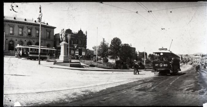 A street scene with a tram labeled "Nº 20" and several buildings, including a large classical structure. A man in a suit stands near the tram on a wet, reflective street.