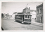A vintage tram numbered 13 with "Victoria St" displayed on its side travels along a paved street lined with historic brick buildings.