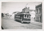 A vintage tram numbered 13 with "Victoria St" displayed on its side travels along a paved street lined with historic brick buildings.