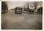 Vintage tram numbered 27 traveling down a tree-lined street in a residential area.  A lady is walking across to the footpath after alighting from the tram.
