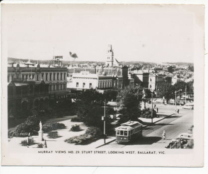 postcard shows a street scene in Ballarat, Victoria, with a tram on the road and a statue in a park. 