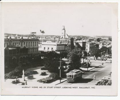 postcard shows a street scene in Ballarat, Victoria, with a tram on the road and a statue in a park. 