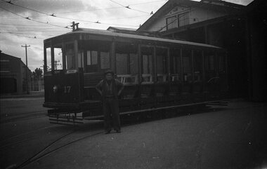 Tram car numbered 17, labeled "DEPOT" and "SPECIAL", sits on tram tracks outside a depot building. A man in work clothes stands beside the tram with his hands on his hips.
